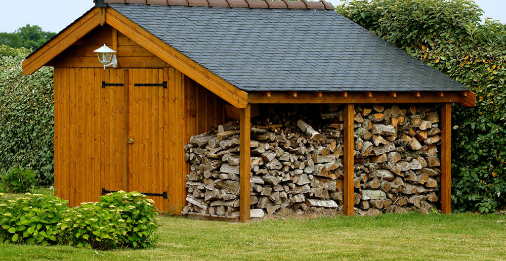 Abri à bois extérieur avec stères de bois sec correctement empilés et organisés par essence dans un jardin pavillonnaire